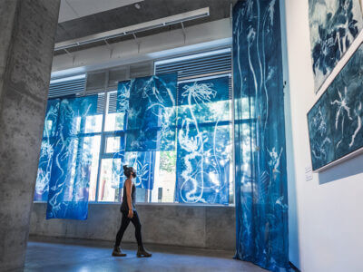 Image of woman in gallery space with blue and white wall hangings all around