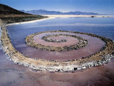 Spiral rock jetty in a lagoon with beach in background